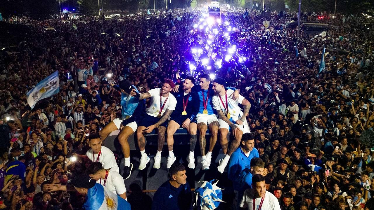 Lionel Messi holds the FIFA World Cup Trophy on board a bus as he celebrates alongside teammates and supporters after winning the Qatar 2022 World Cup tournament in Ezeiza, Buenos Aires province, Argentina. Credit: AFP Photo
