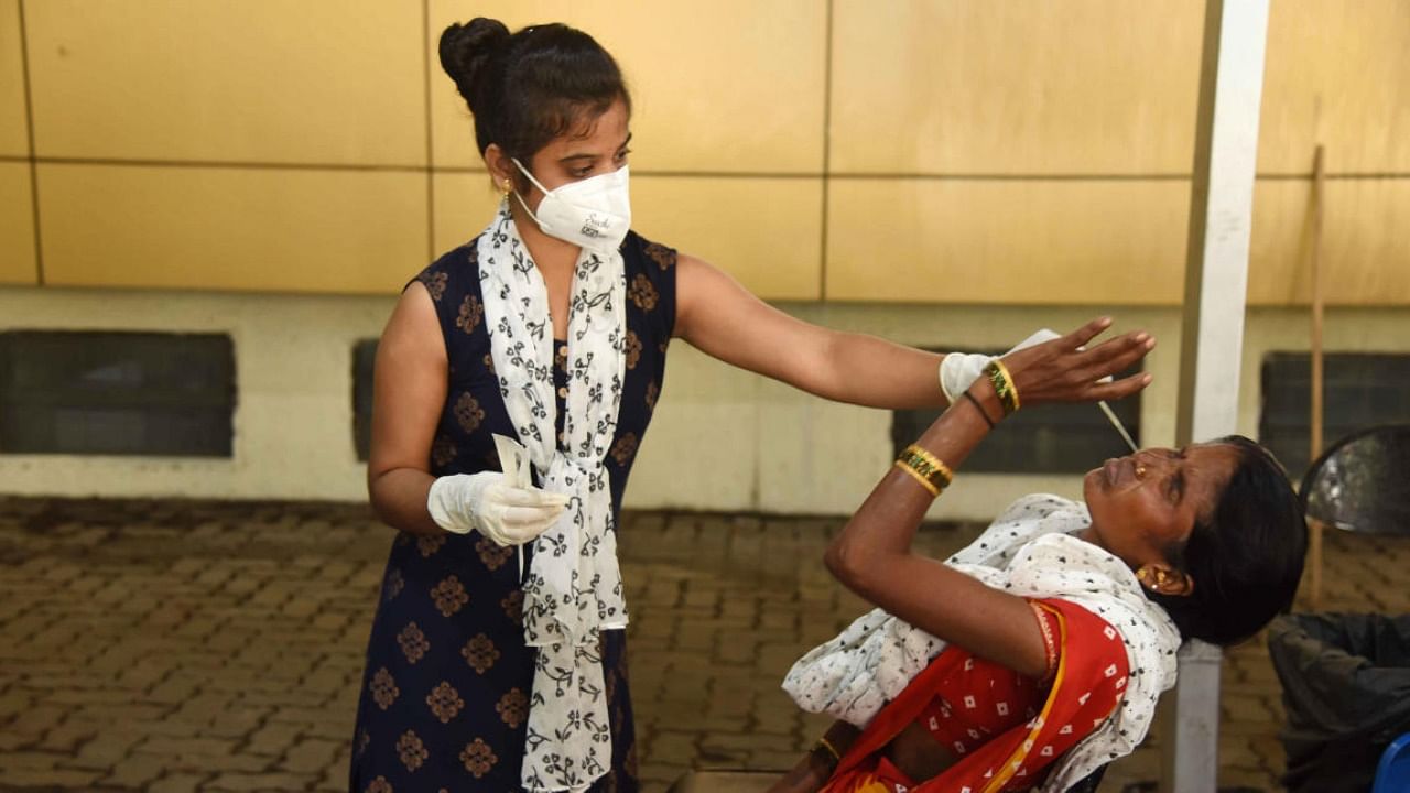 A medic collects swab sample of a woman for Covid-19 test at a hospital in Mumbai. Credit: PTI File Photo