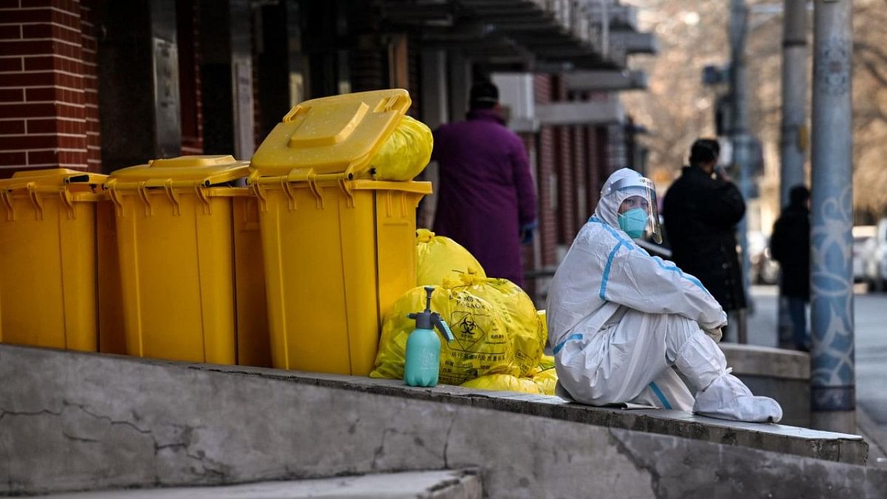 A worker wearing personal protective equipment (PPE) sits next to waste material outside a fever clinic amid the Covid-19 pandemic in Beijing. Credit: AFP Photo