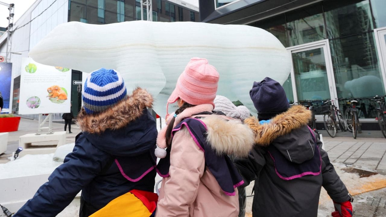 Children stand next to a polar bear ice sculpture, designed to melt and raise awareness of climate change, in the Quartier des spectacles, during COP15. Credit: Reuters photo