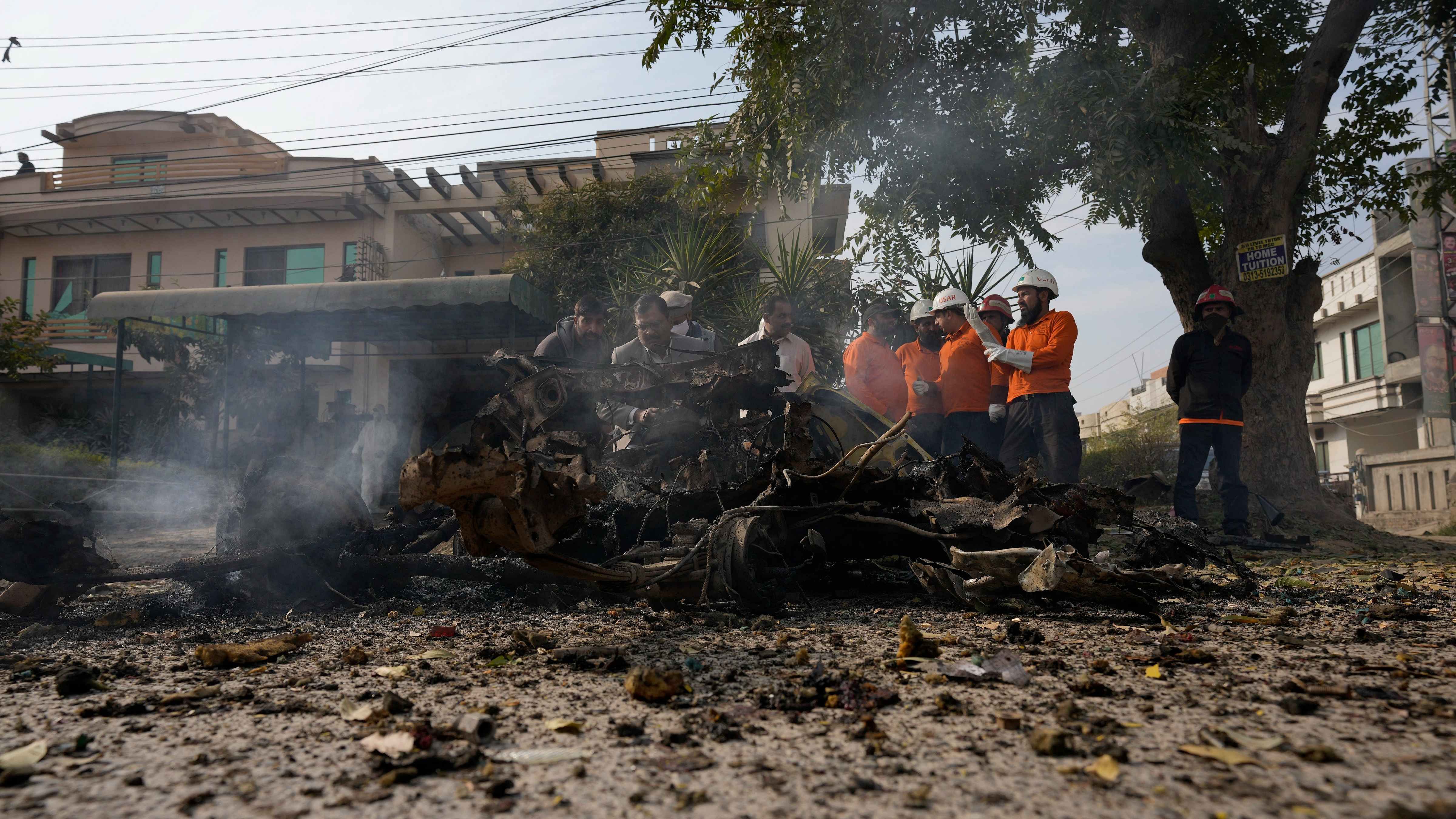 Security officials examine the wreckage of a car at the site of bomb explosion, in Islamabad. Credit: AP/PTI Photo