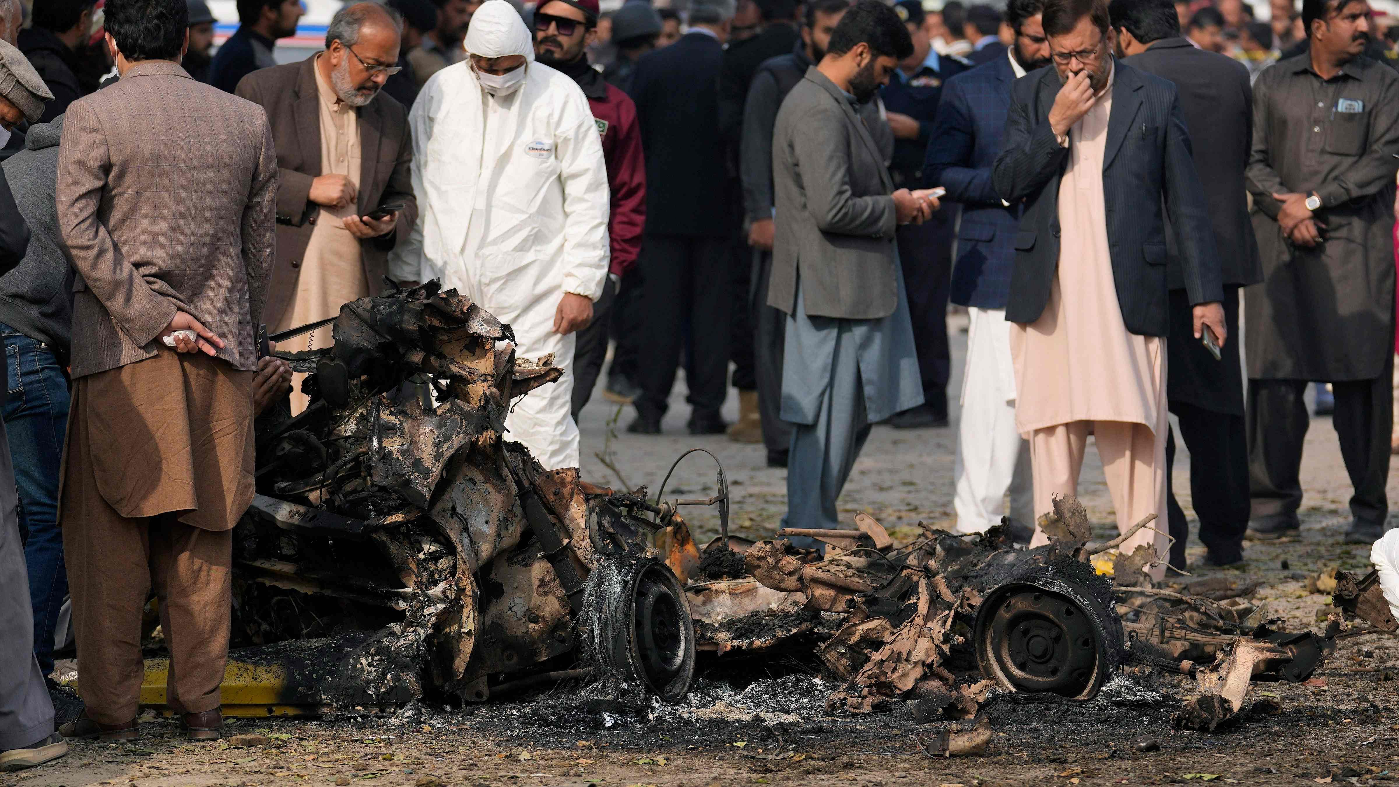 Investigators collect evidence from the wreckage of a car at the site of bomb explosion, in Islamabad, Pakistan. Credit: AP/PTI Photo