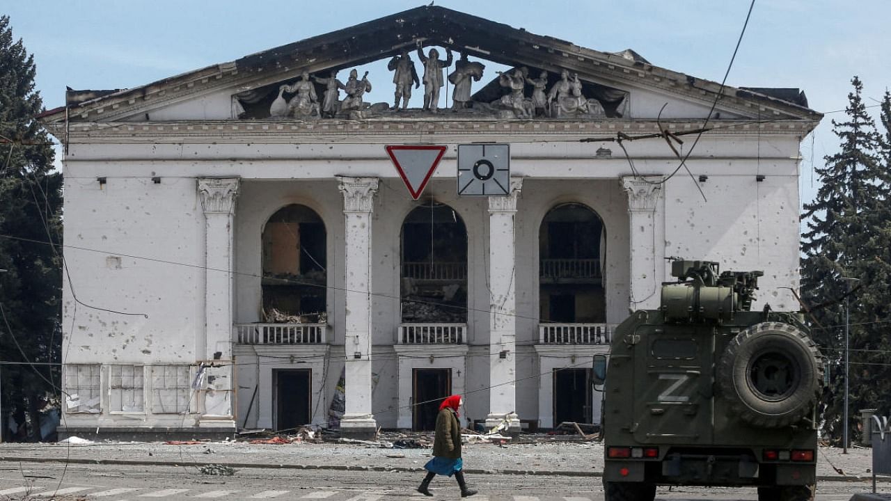 A woman walks next to an armoured vehicle of pro-Russian troops in front of a theatre in Mariupol destroyed in a bombardment on March 16, 2022. Credit: Reuters file photo