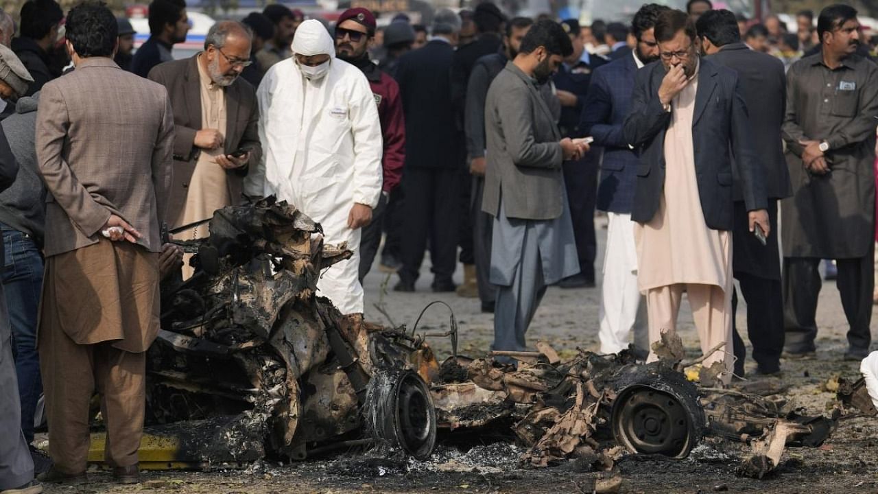Investigators collect evidence from the wreckage of a car at the site of bomb explosion, in Islamabad. Credit: AP/PTI Photo