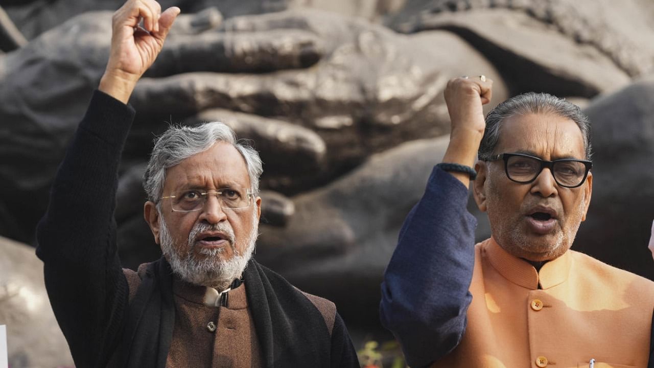 BJP MPs Sushil Kumar Modi and Radha Mohan Singh raise slogans during protest near the Gandhi Statue demanding compensation for the victims of Saran hooch tragedy, during Winter Session of Parliament, in New Delhi. Credit: PTI Photo
