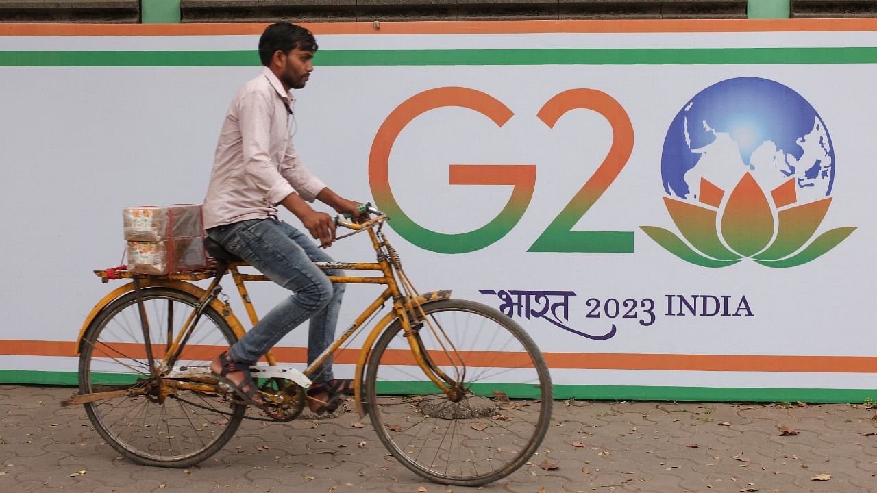 A man rides a bicycle past the hoarding of India's G20 presidency, on a street in Mumbai. Credit: Reuters photo