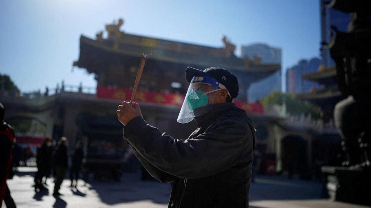 A man wearing a protective masks and face shield worships at the Buddhist Jing'an Temple, as the Covid-19 outbreaks continue in Shanghai. Credit: Reuters photo