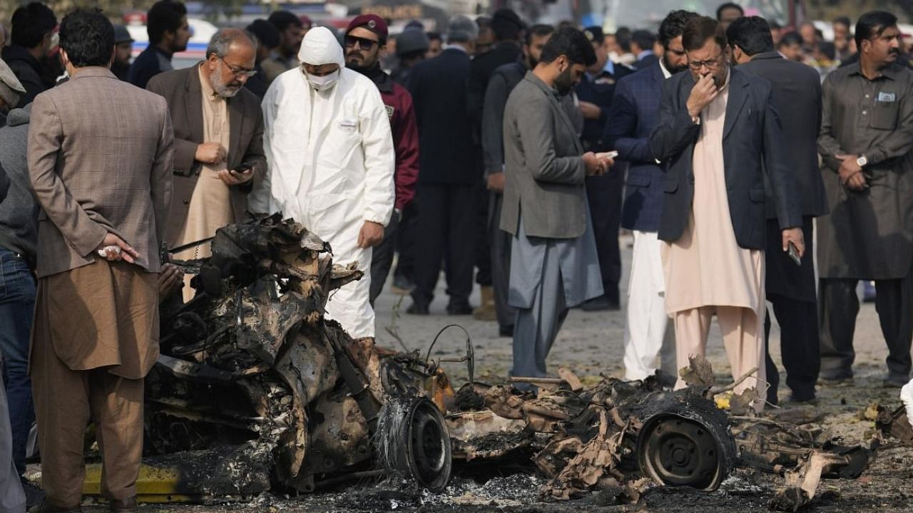 Investigators collect evidence from the wreckage of a car at the site of bomb explosion, in Islamabad