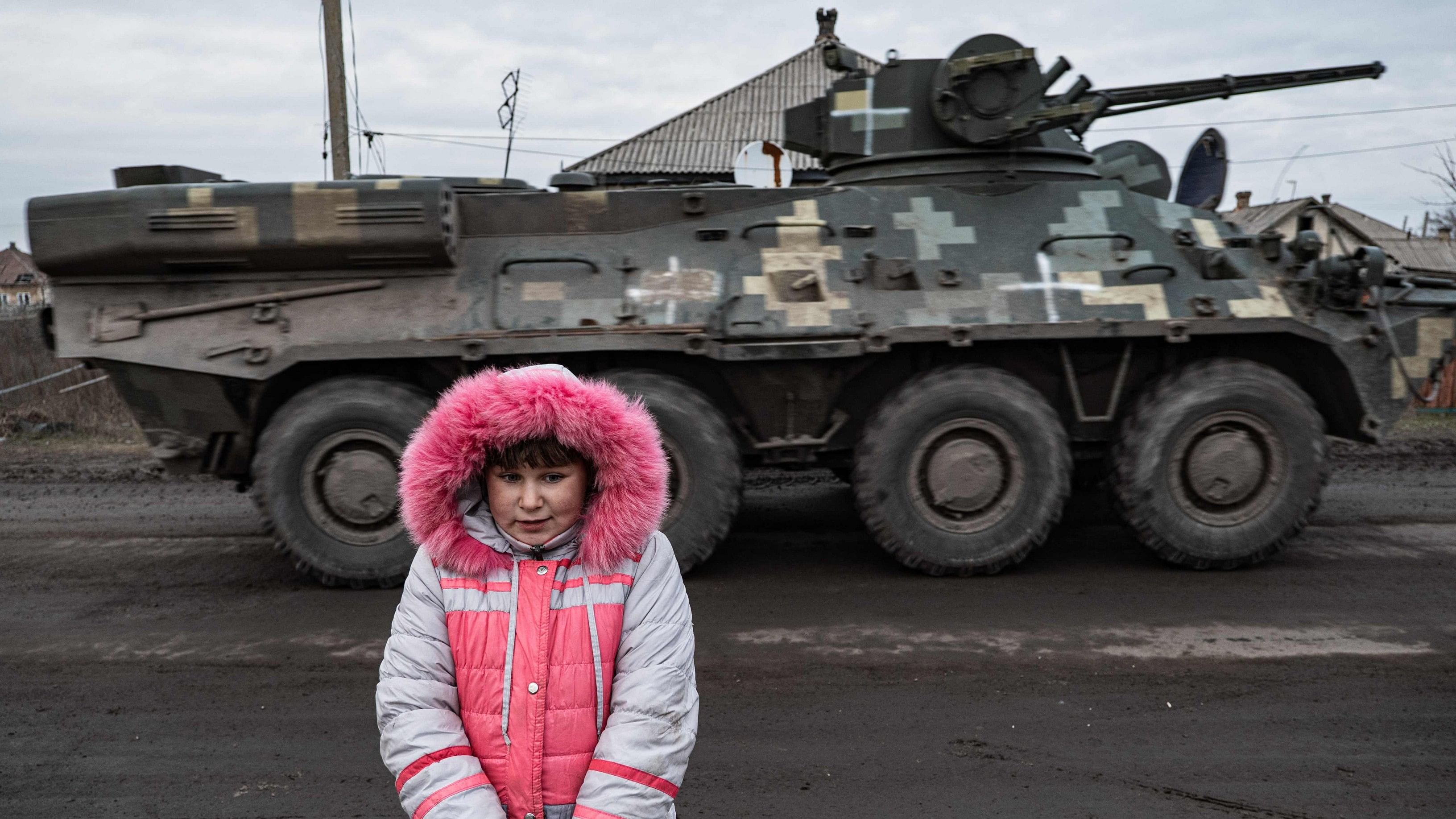 Lisa Shtanko, 8-year-old, looks on as a military vehicle passes behind in front of her house in the city of Lyman, eastern Ukraine on December 23, 2022. Credit: AFP Photo