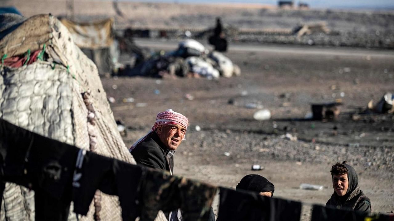 A man looks on while sitting outside a tent at a camp for those displaced by conflict in the countryside near Syria's northern city of Raqa on December 19, 2022. Credit: AFP Photo