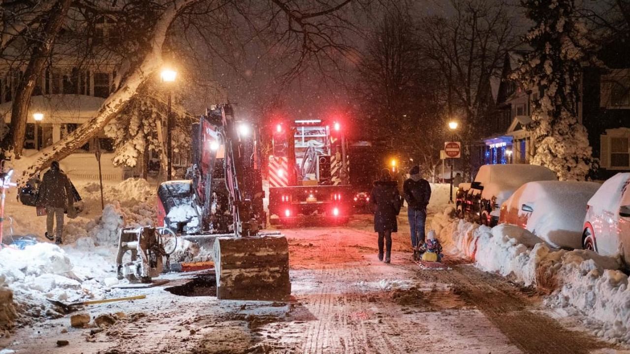 Pedestrians walk past workers attempting to repair a water line in Buffalo, New York. Credit: AFP