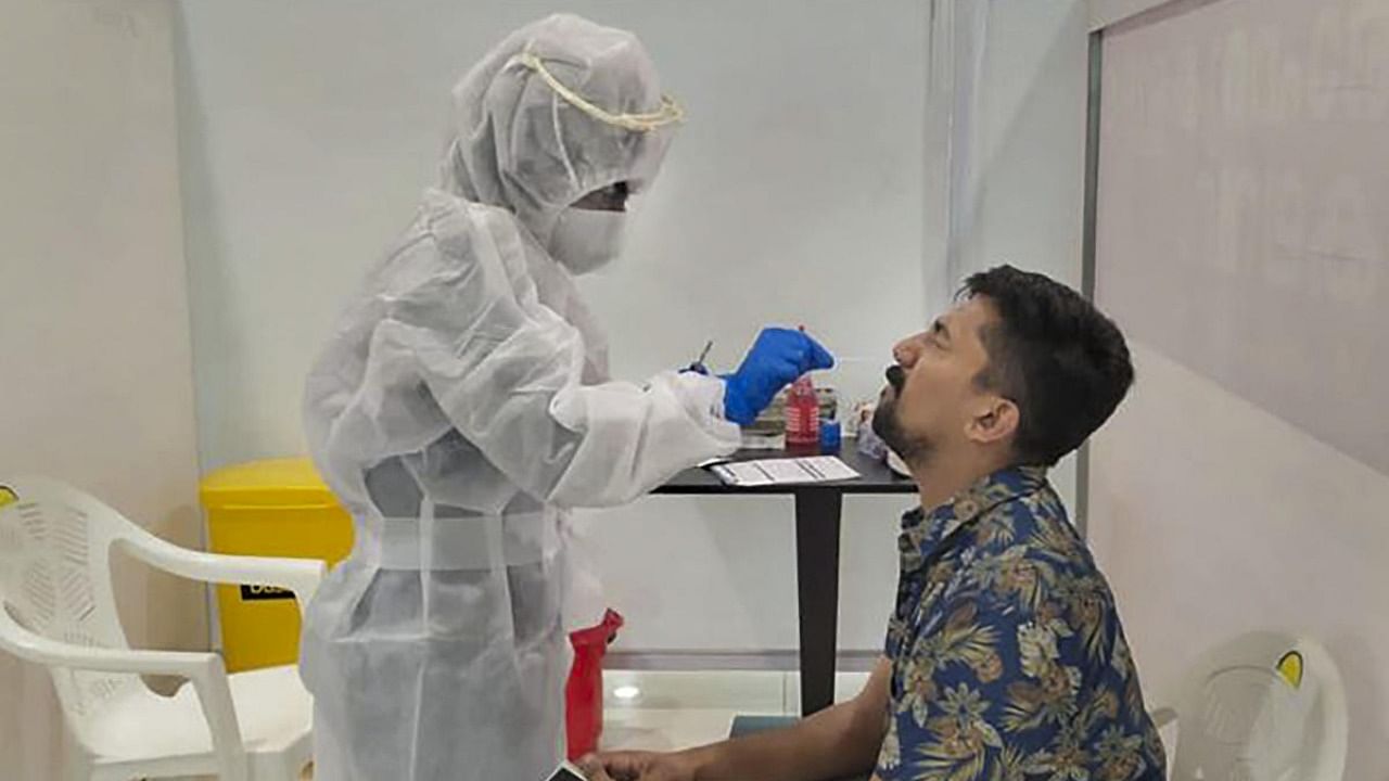 A health worker collects a swab sample of a passenger as random Covid-19 testing starts at various airports across the country in the wake of rising cases of Coronavirus globally. Credit: PTI Photo