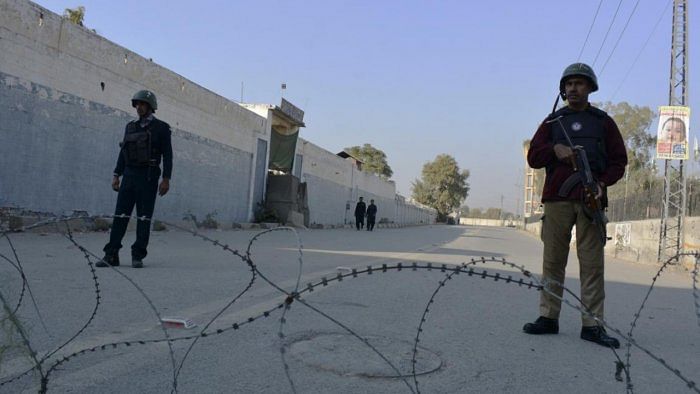 Pakistan security forces stand guard a road leading to a counter-terrorism centre as officials began clearing the compound seized earlier by Taliban militants. Credit: AP/PTI 