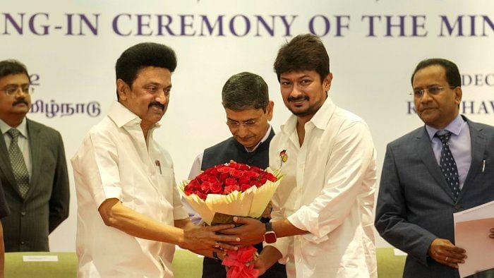 Tamil Nadu Chief Minister M K Stalin presents a bouquet to DMK MLA Udhayanidhi Stalin during the latter's swearing-in ceremony as Tamil Nadu Minister, at Raj Bhavan in Chennai. Credit: PTI Photo