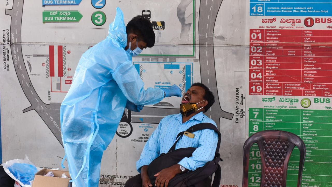 A healthcare worker collects swab samples from commuters near Majestic in Bengaluru. Credit: DH Photo/Pushkar V