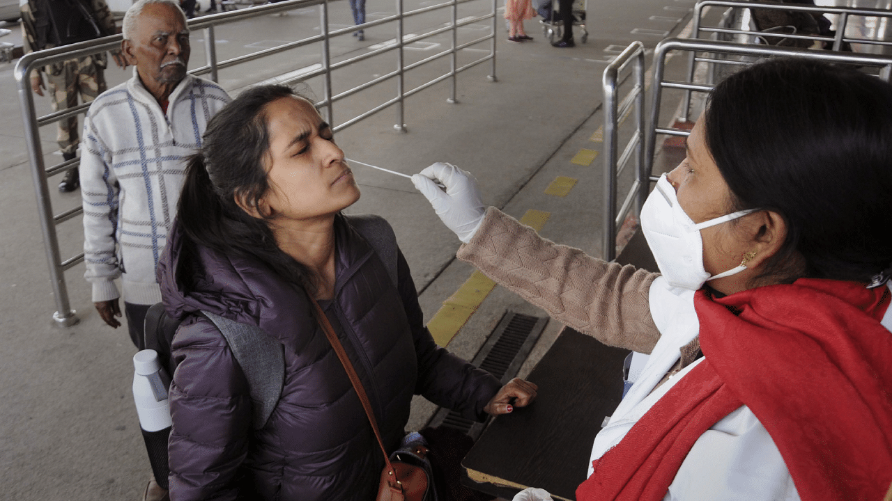 A medic takes swab sample from an air passenger for Covid-19 test at the Birsa Munda International Airport. Credit: PTI Photo