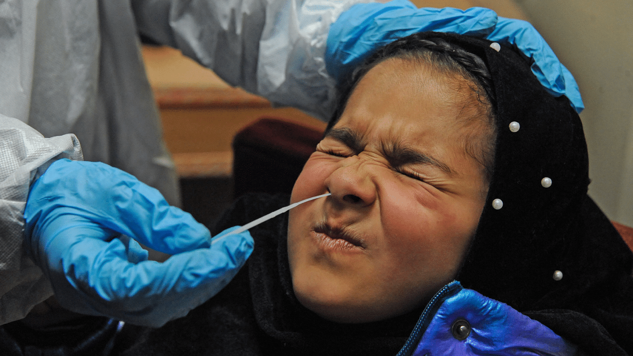 A girl reacts as a health worker wearing personal protective equipment takes nasal swab samples to test for Covid-19. Credit: AFP Photo