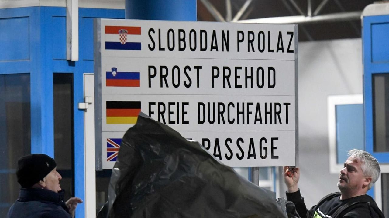 Customs personnel unveil a sign as vehicles pass without stopping at the Bregana border crossing between Croatia and Slovenia on January 1, 2023. Credit: AFP Photo