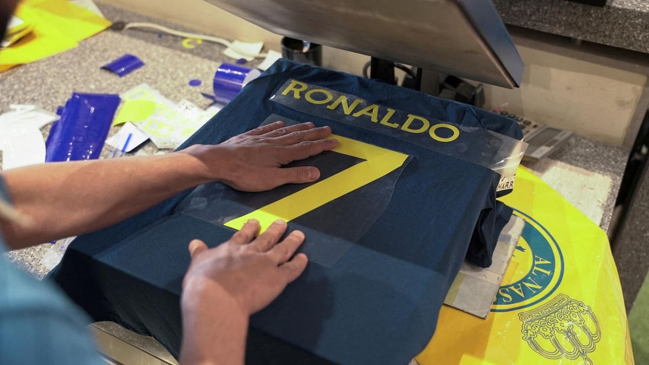 A staff member heat presses an Al Nassr jersey with Cristiano Ronaldo's surname on the back. Credit: Reuters Photo
