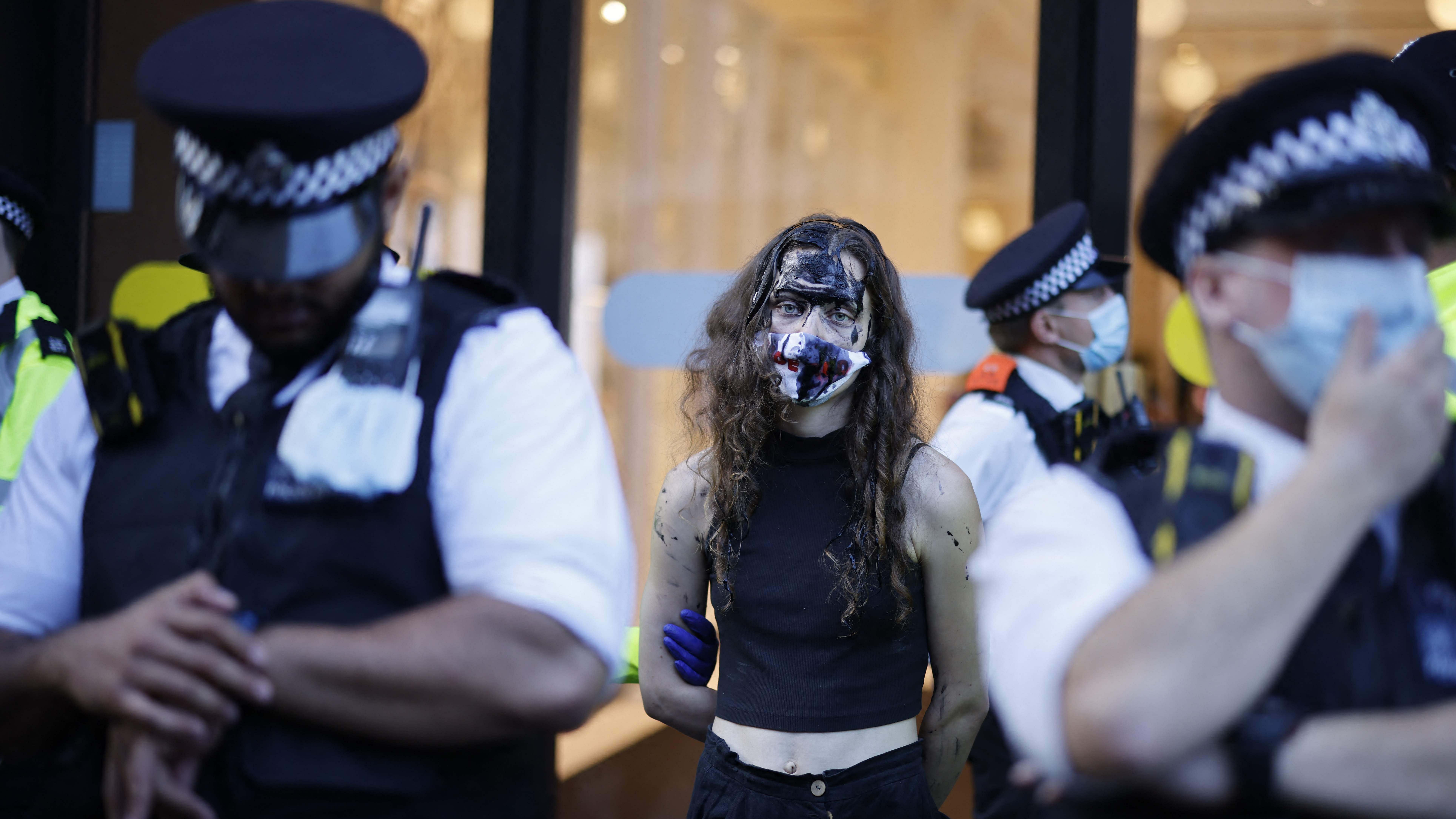 Police officers detain a climate activist from the Extinction Rebellion group outside the Selfridges store in central London on August 24, 2021 where the group demonstrated against the use of fossil fuel. Credit: AFP Photo
