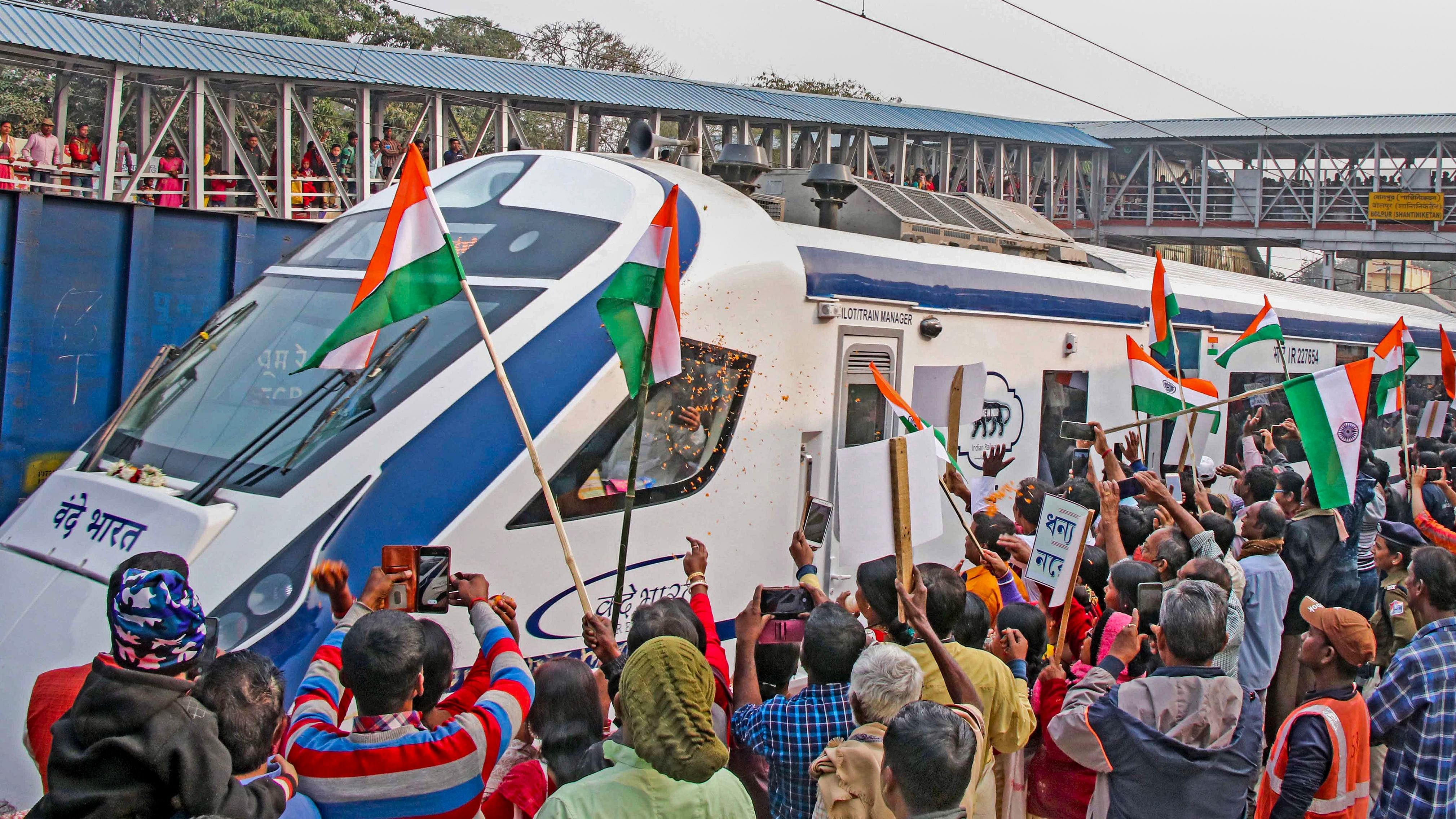  People wave the national flags upon the arrival of Vande Bharat Express train at Bolpur railway station, in Birbhum district. Credit: PTI Photo