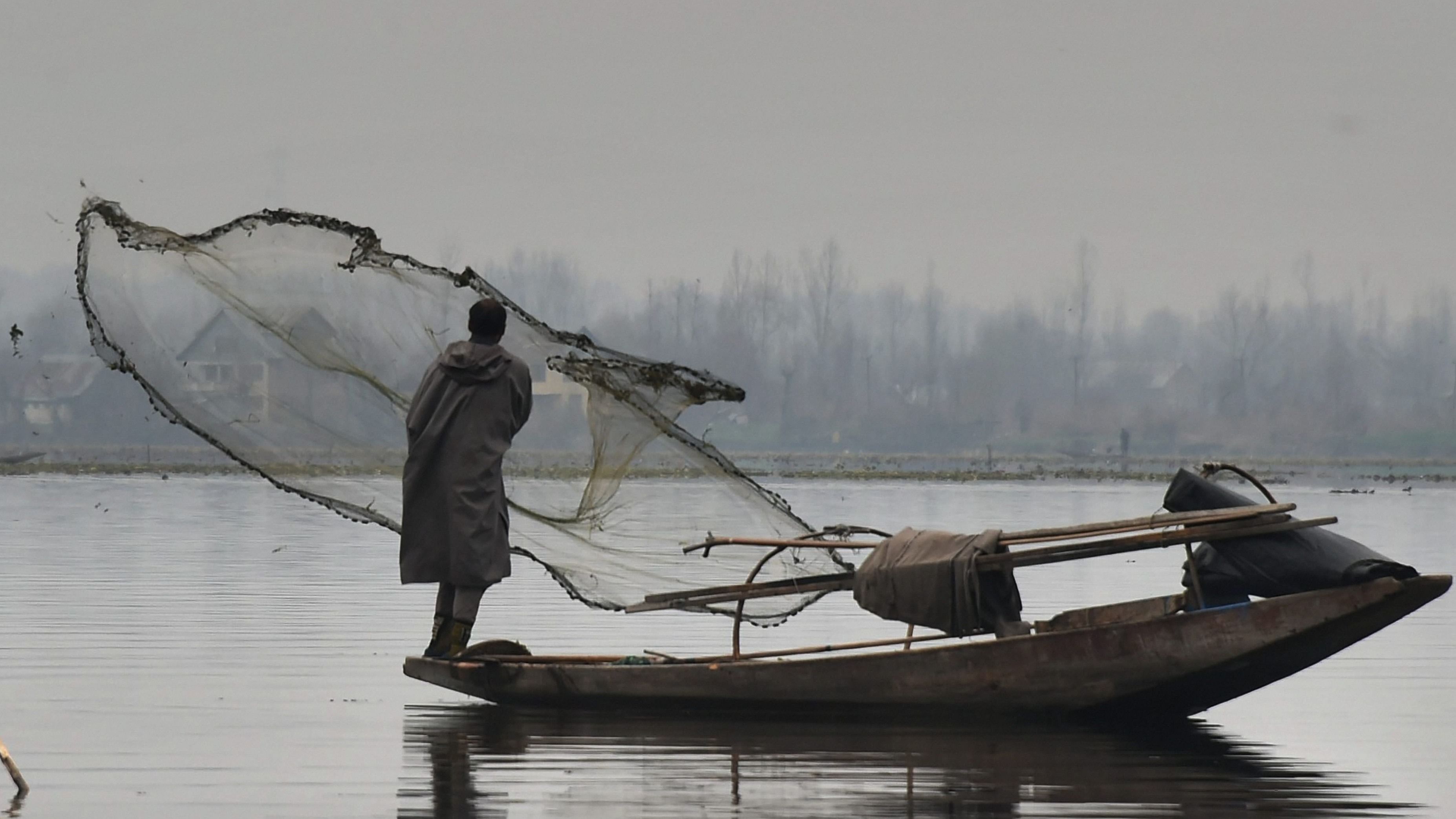 File photo of a fisherman casting his net at Dal Lake during a cold winter morning, in Srinagar. Credit: PTI Photo