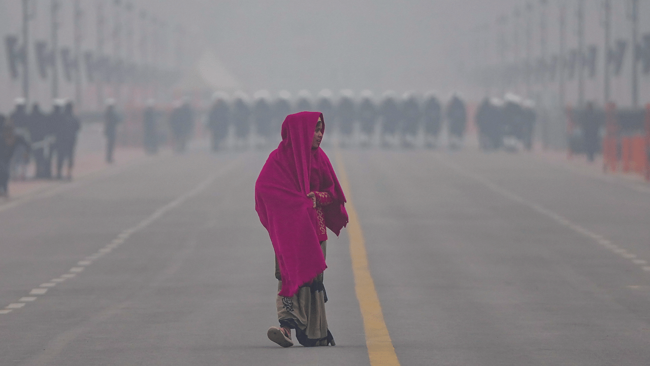 A woman wrapped in warm clothes walks on the Kartavya Path during a cold and foggy winter morning, in New Delhi. Credit: PTI Photo