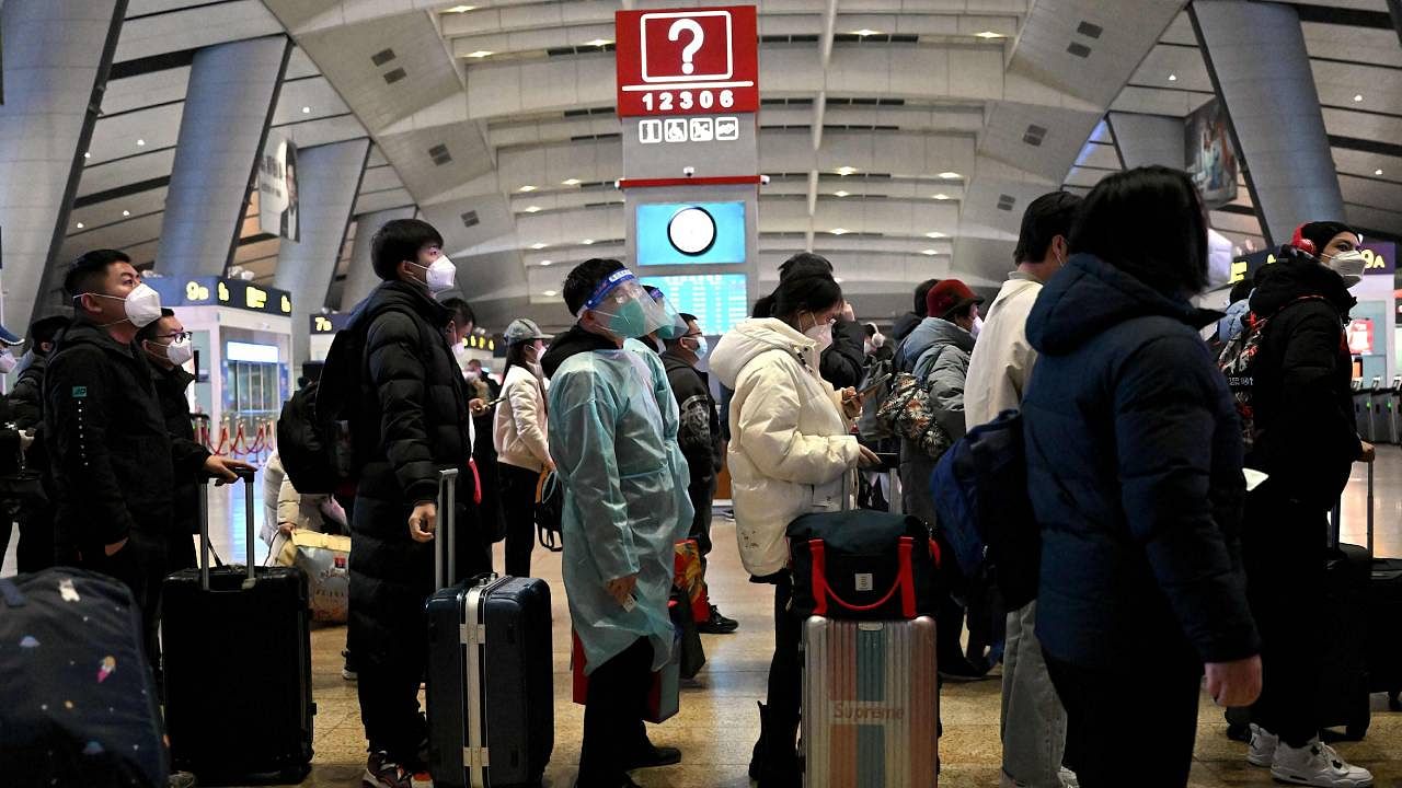 Passengers, some wearing personal protective gear to halt the spread of Covid-19, queue at a train station in Beijing. Credit: AFP Photo