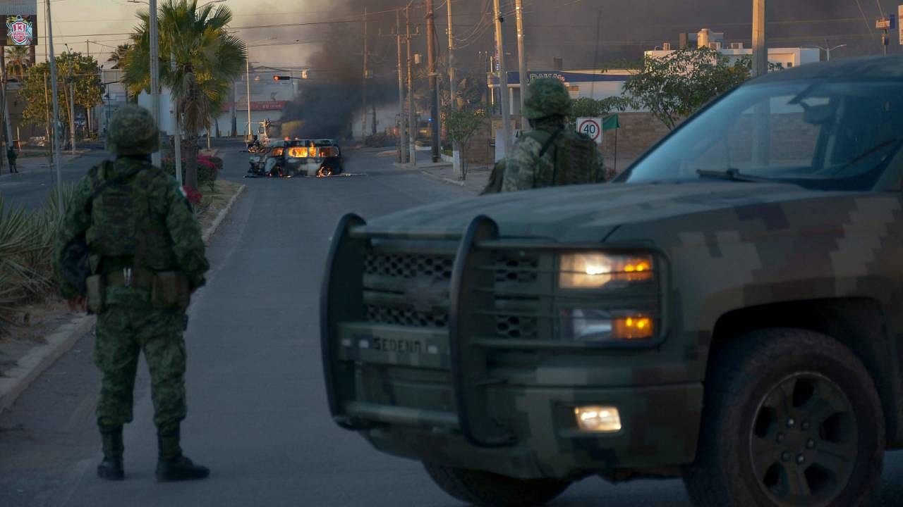 Mexicans soldiers stand guard near burning vehicles on a street during an operation to arrest the son of Joaquin "El Chapo" Guzman, Ovidio Guzman, in Culiacan, Sinaloa state, Mexico. Credit: AFP Photo