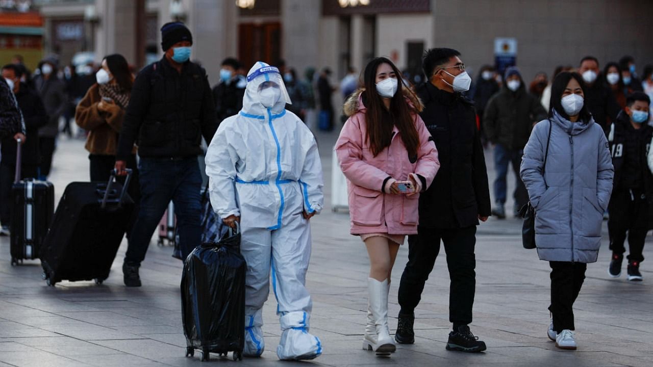 A traveller wearing a protective suit walks outside Beijing Railway Station as the annual Spring Festival travel rush starts amid Covid-19, ahead of the Chinese Lunar New Year, in Beijing. Credit: Reuters photo