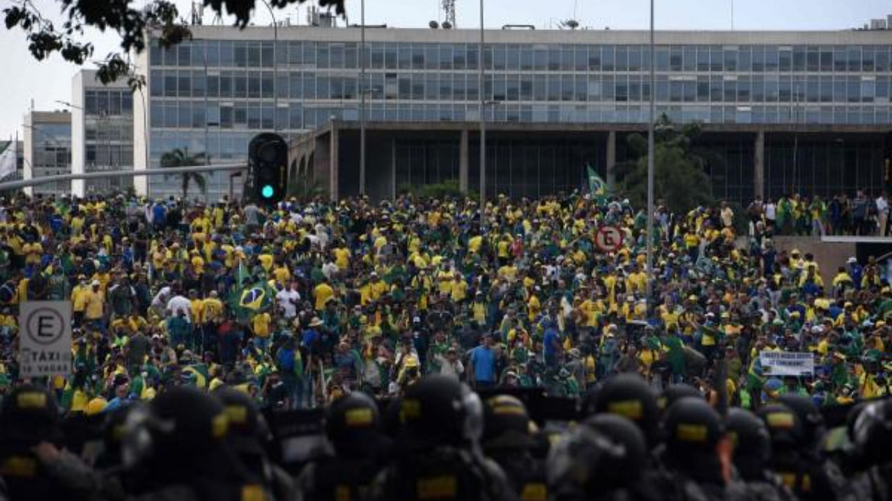 Supporters of Brazilian former President Jair Bolsonaro invading several governmental building are confronted by security forces (foreground) in Brazil. Credit: AFP Photo