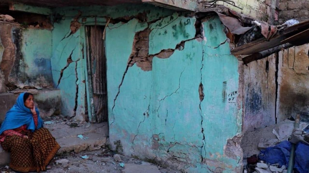 A resident sits next to a cracked wall of her house at Joshimath in Chamoli district of  Uttarakhand on January 8, 2023. Credit: AFP Photo