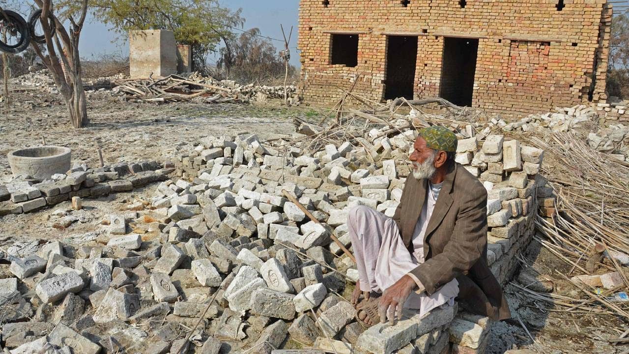 A flood-affected resident sits besides the debris of his damaged house in the flood-hit area of Dera Allah Yar in Jaffarabad district of Balochistan province. Credit: AFP Photo