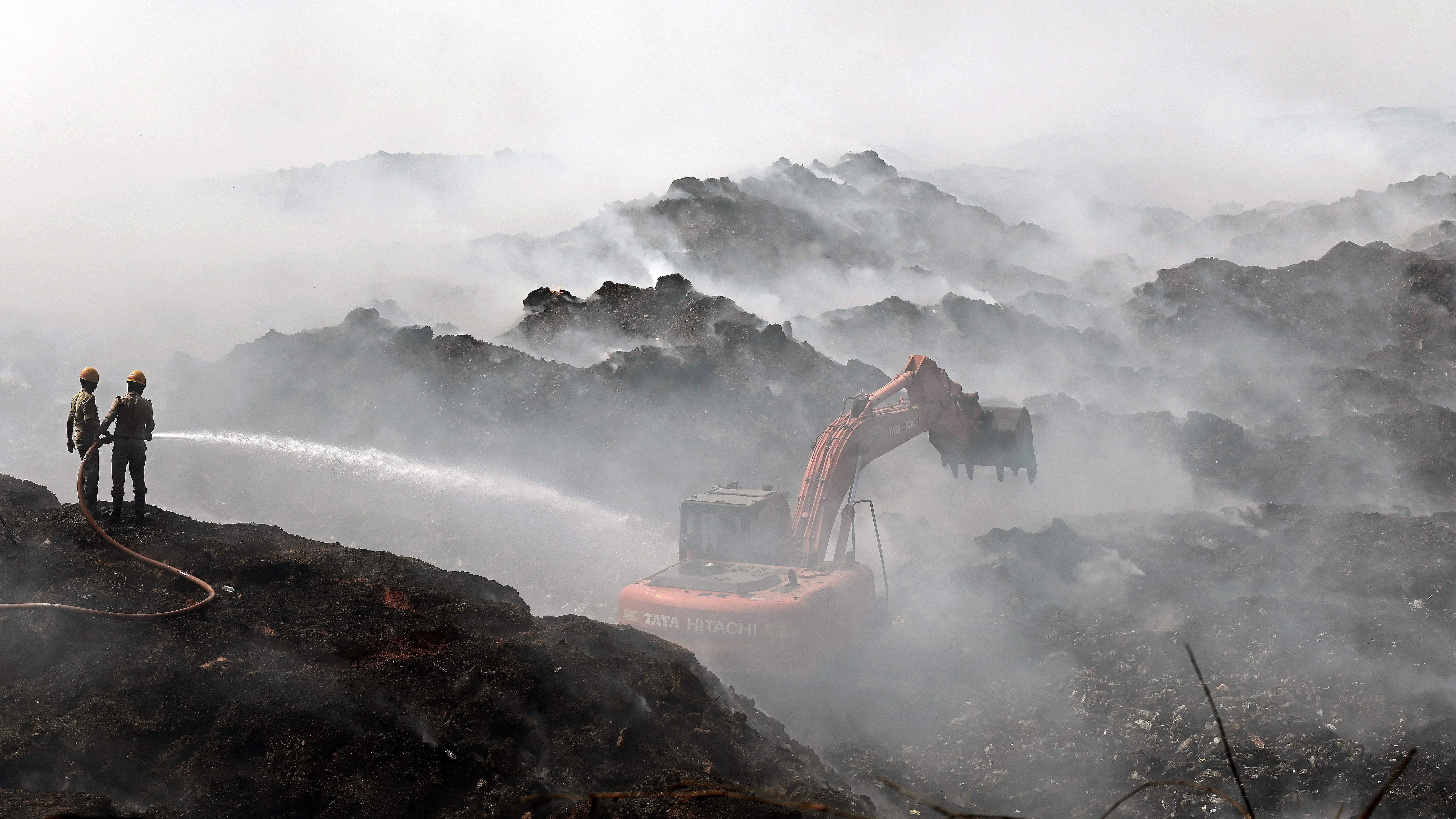 Fire and emergency service personnel continue to douse smoke emanating at landfill site in Pacchanady on Monday. Credit: DH Photo/Fakruddin H