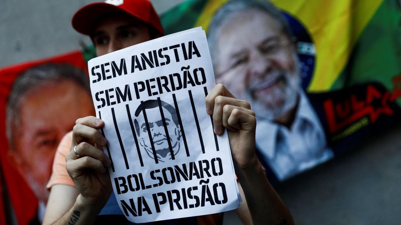 A pro-democracy demonstrator holds a sign during a march with an image depicting far-right former President Jair Bolsonaro and the writing "No amnesty, no pardon, Bolsonaro to prison". Credit: Reuters Photo