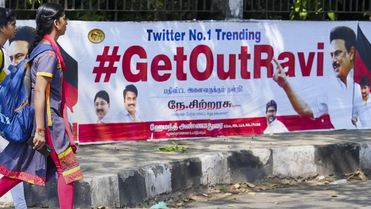 Young women walk past posters that read '#GetOutRavi' pasted on a wall, a day after Tamil Nadu Governor R.N. Ravi walked out of the State Assembly during Assembly Session, in Chennai, Tuesday, Jan. 10, 2023. Credit: PTI Photo