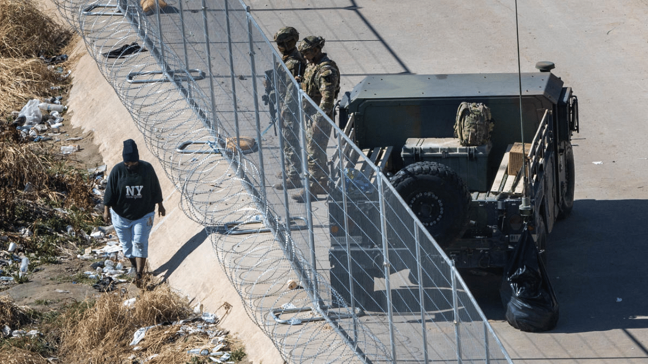 An immigrant passes Texas National Guard soldiers at the US Mexico border. Credit: Getty Images via AFP