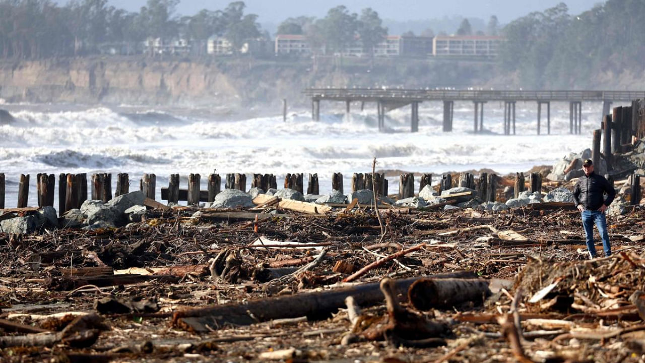 A person stands amid storm debris washed up on the beach in California. Credit: Getty Images via AFP 