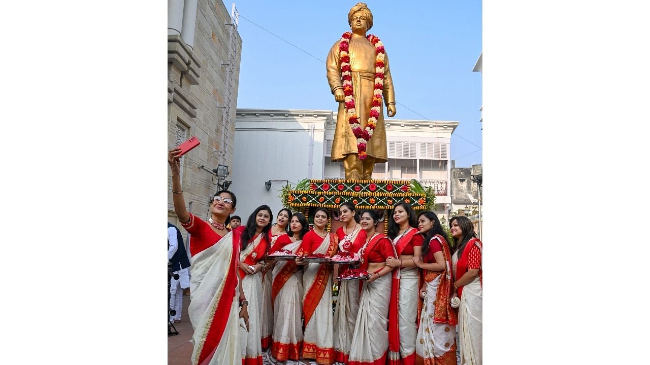 Students in traditional attire click a selfie with the statue of Swami Vivekananda. Credit: PTI Photo