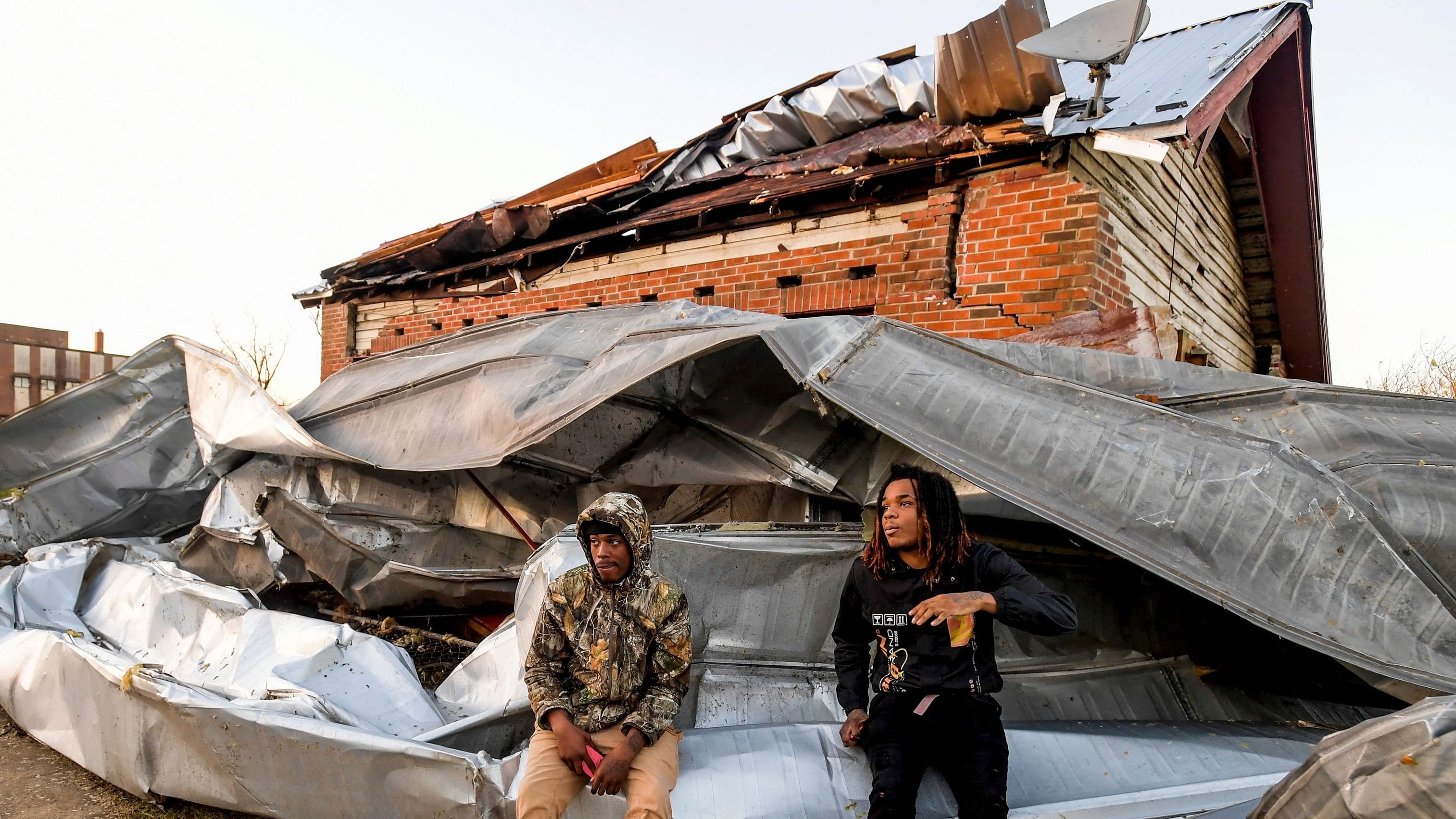 Cordel Tyus and Devo McGraw sit on roofing that blew off of an industrial building and wrapped around their house after a tornado ripped through Selma, Alabama, US. Credit: Reuters Photo