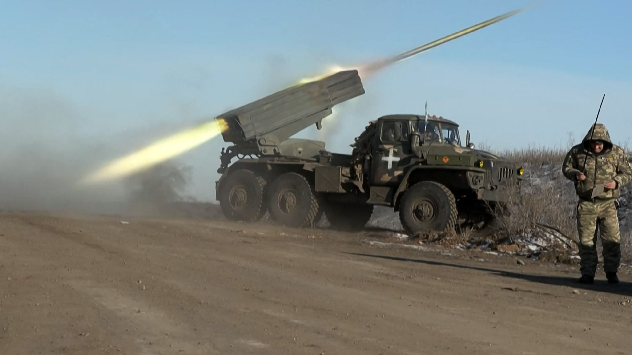 This grab taken from AFP video footage shows a member of Ukraine's military looking away as a BM-21'Grad' MLRS 122mm rocket launcher fires on the outskirts of Soledar on January 11. Credit: AFP Photo