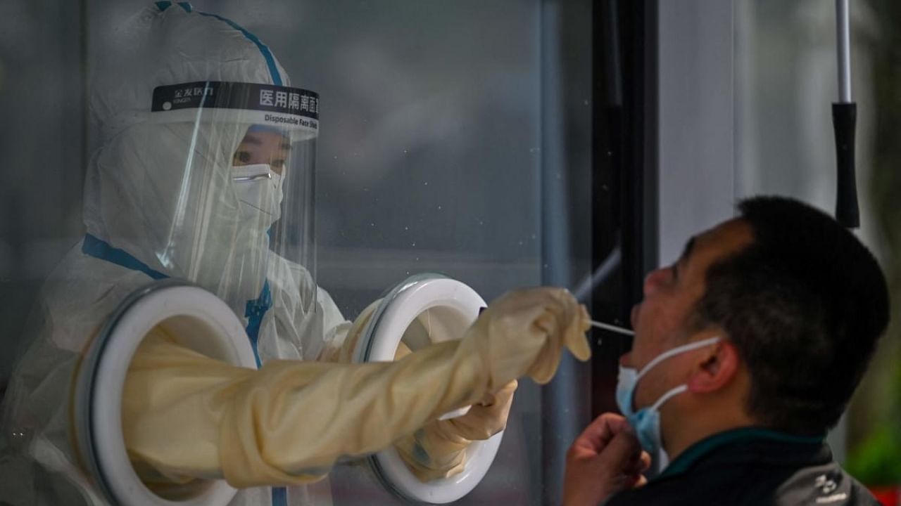 A health worker takes a swab sample from a man during a Covid-19 coronavirus lockdown in the Jing'an district in Shanghai on May 27, 2022. Credit: AFP Photo