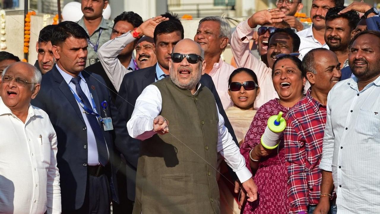 Home Minister Amit Shah (C) flies a kite as Chief Minister of Gujarat Bhupendra Patel (L) watches during an event to mark the occasion of Makar Sankranti. Credit: AFP Photo