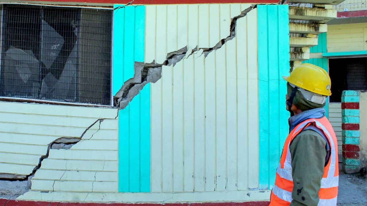 A worker looks at cracks that appeared in a PWD Guest House, in land subsidence affected area in Joshimath, Monday, Jan. 16, 2023. Credit: PTI Photo