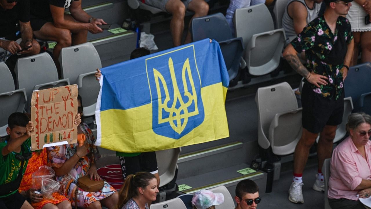 A spectator holds up a Ukrainian flag during the men's singles match between Russia's Andrey Rublev and Austria's Dominic Thiem on day two of the Australian Open tennis tournament in Melbourne. Credit: AFP Photo