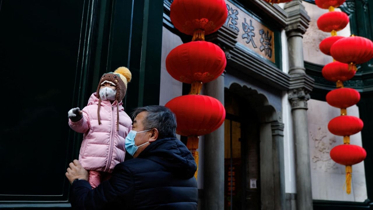 An elderly person holds a child near lanterns decorating a shop ahead of the Chinese Lunar New Year, in Beijing, China. Credit: Reuters photo