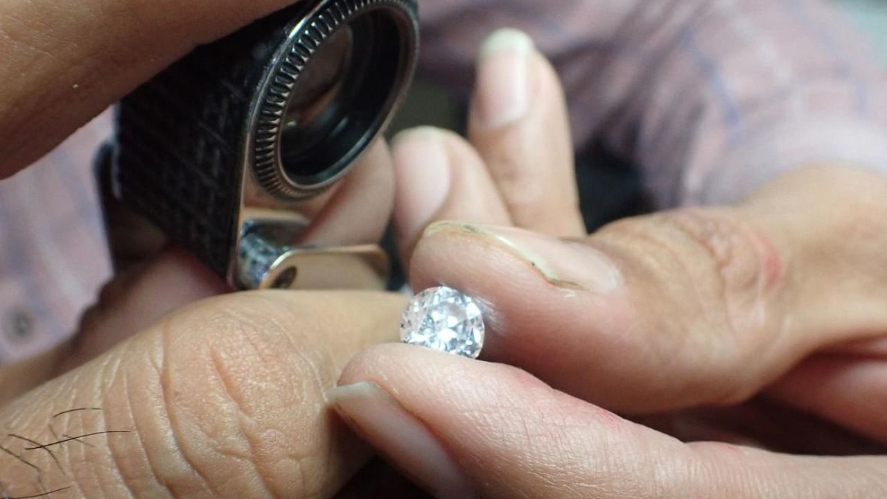 A worker checks a diamond at a diamond polishing workshop in Ahmedabad. Credit: AFP Photo