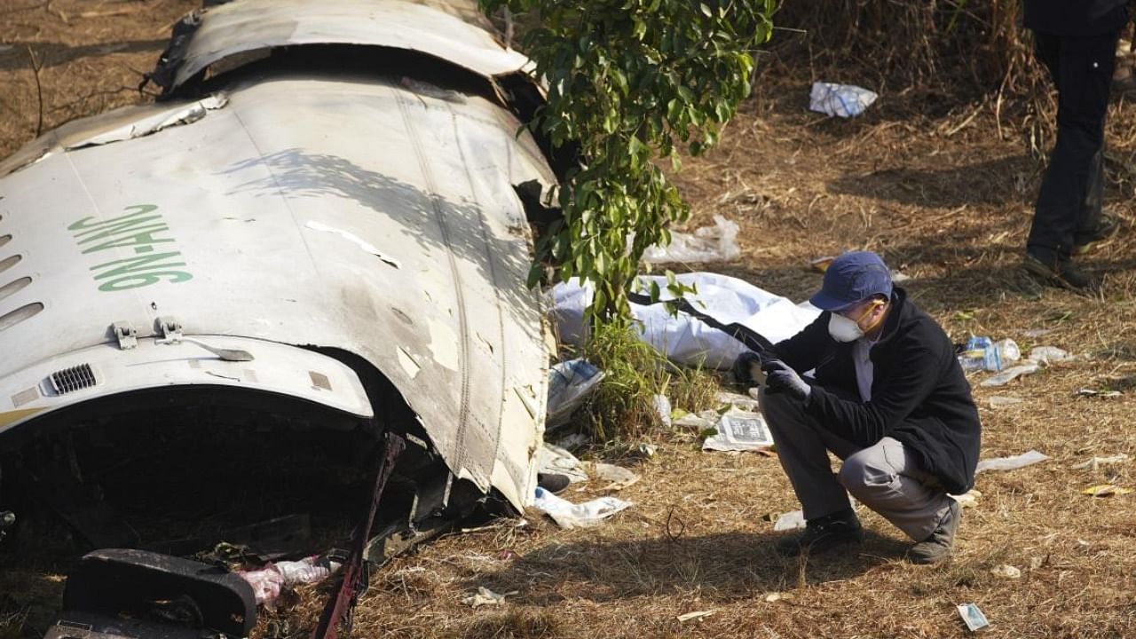 A French investigator takes a photo of the wreckage of a passenger plane at the crash site, in Pokhara, Nepal. Credit: AP/PTI