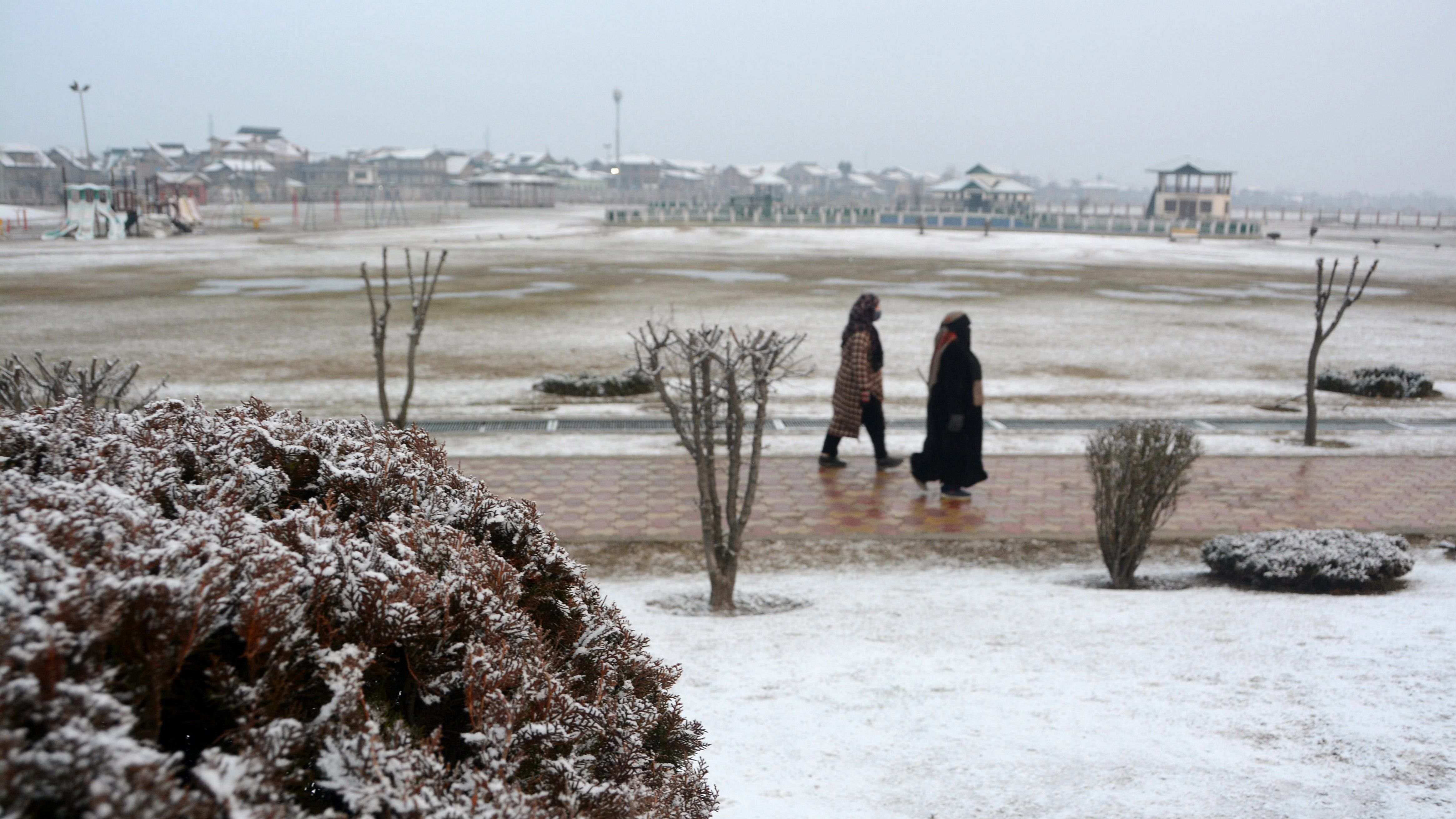 People walk in a park after fresh snowfall in Srinagar. Credit: PTI Photo