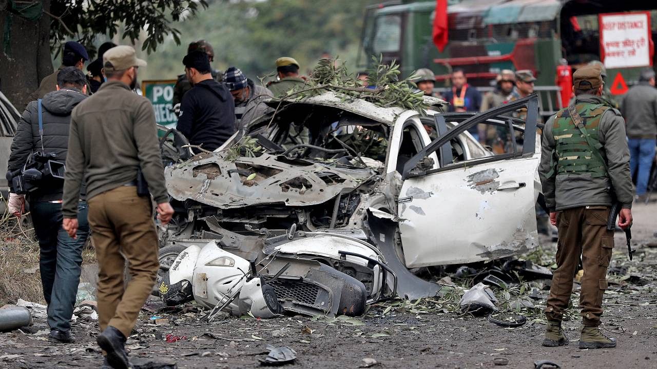 Security force personnel stand guard next to a damaged vehicle after a bomb blast in Narwal area of Jammu. Credit: Reuters Photo